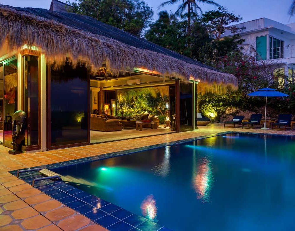 A dazzling view of the Balinese style hut and infinity pool at night.